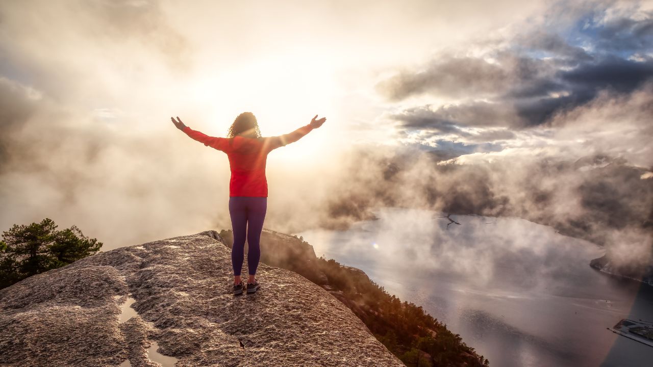 Frau genießt den Sonnenaufgang am Gipfel -Mindset Coaching